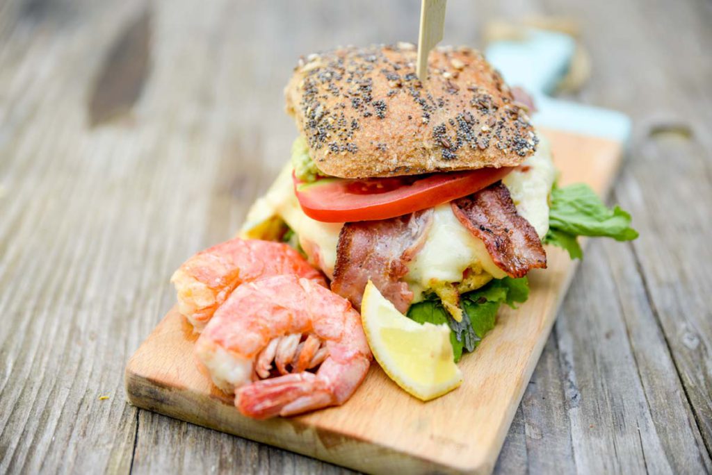Knödel grillen kann so lecker sein, z.B. in Form dieses Burgers mit Knödelpatty, Salat, Tomate, Käse, Bacon und Garneln.